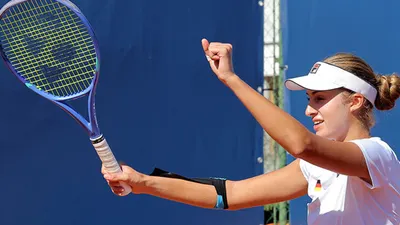 Tennis player Milena Steinkamp celebrates on a clay court with a raised fist and racket in hand.